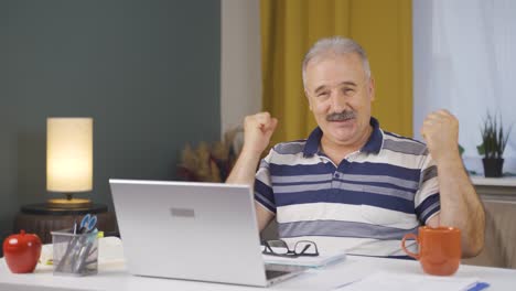 Home-office-worker-old-man-experiencing-joy-looking-at-camera.